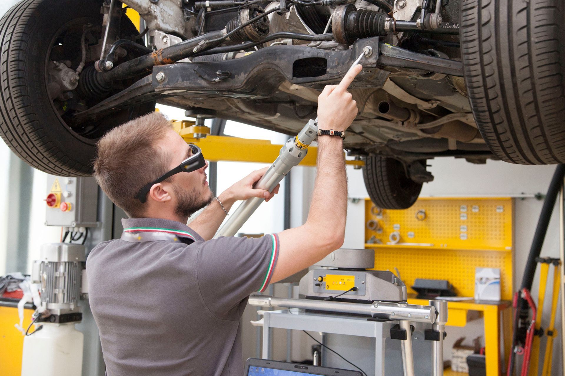 Mechaniker der Messungen unter dem Auto durchführt