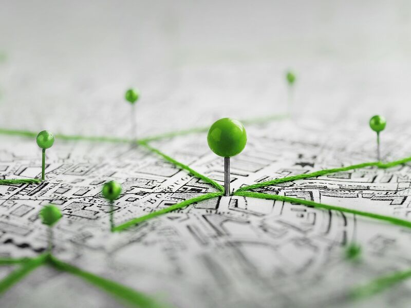 Mehrere Pins auf einer Stadtkarte die mit einem Faden verbunden sind